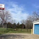 To the left is the large sign for the facility and to the right is a drive-up storage unit with indoor units that are climate-controlled