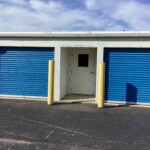 Drive-Up storage units with blue roll-up doors with an indoor units entryway door