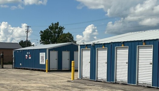 Corner of drive up blue metal storage units with white doors