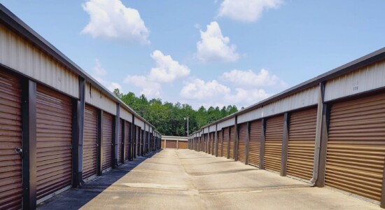 Row of outdoor drive-up storage units with brown doors