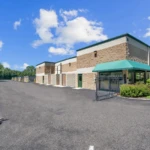 The entrance gate to the storage facility including indoor climate-controlled storage units, drive-up storage units, and an office with on-site management