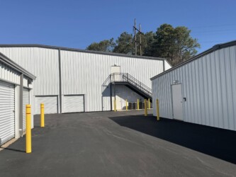 Outdoor driveway with drive-up storage units and view of indoor temperature-controlled storage unit buildings