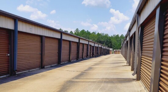 Row of outdoor drive-up storage units with brown doors